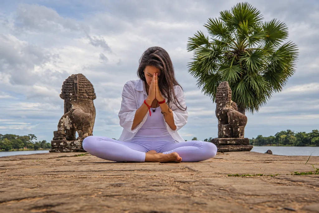 Marielisa Padilla with hands in prayer at Srah Srang terrace, lake behind